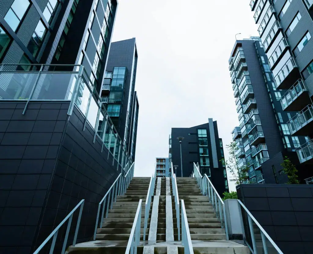 A photo of an outdoor stone staircase, surrounded by tall blocks of apartments with black cladding.