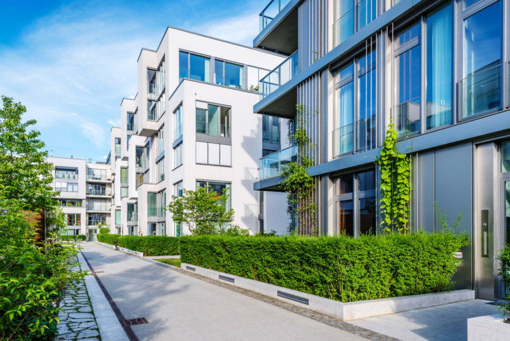 A luxury complex of white apartment buildings and green spaces.
