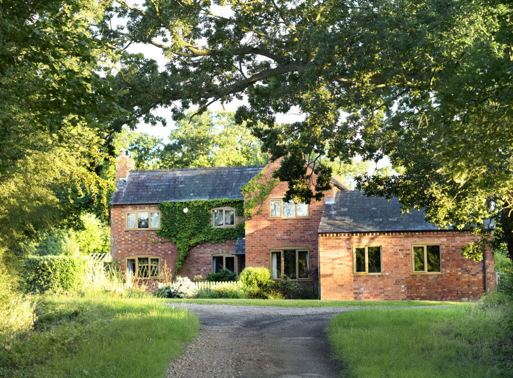 A large family farmhouse surrounded by grass and a driveway