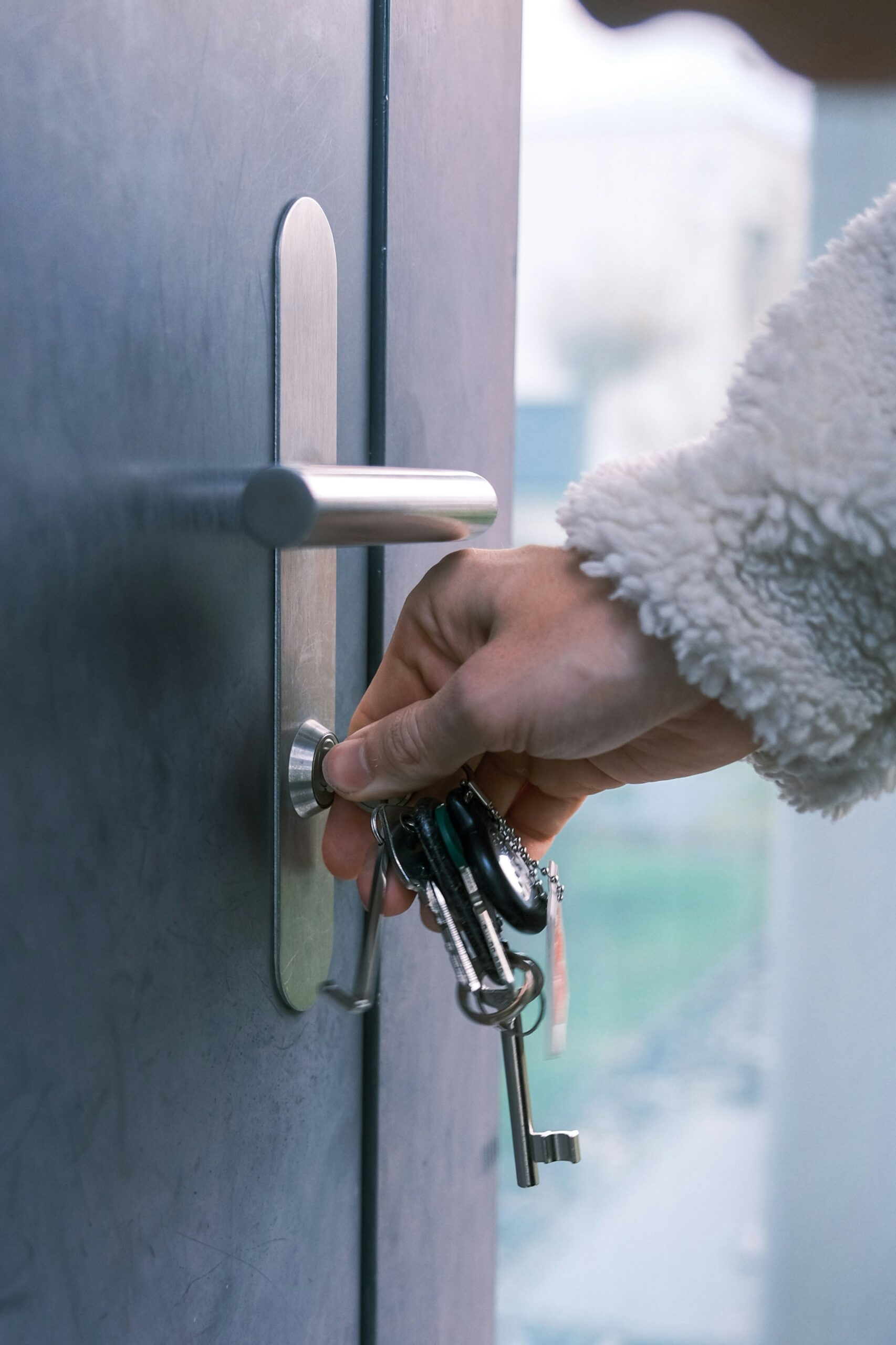 A hand holding keys locking a door