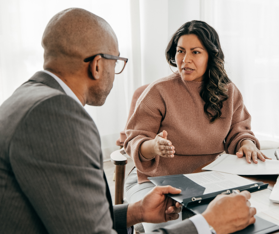 A man and a woman discussing a mortgage application together. They are sat opposite each other at a table.